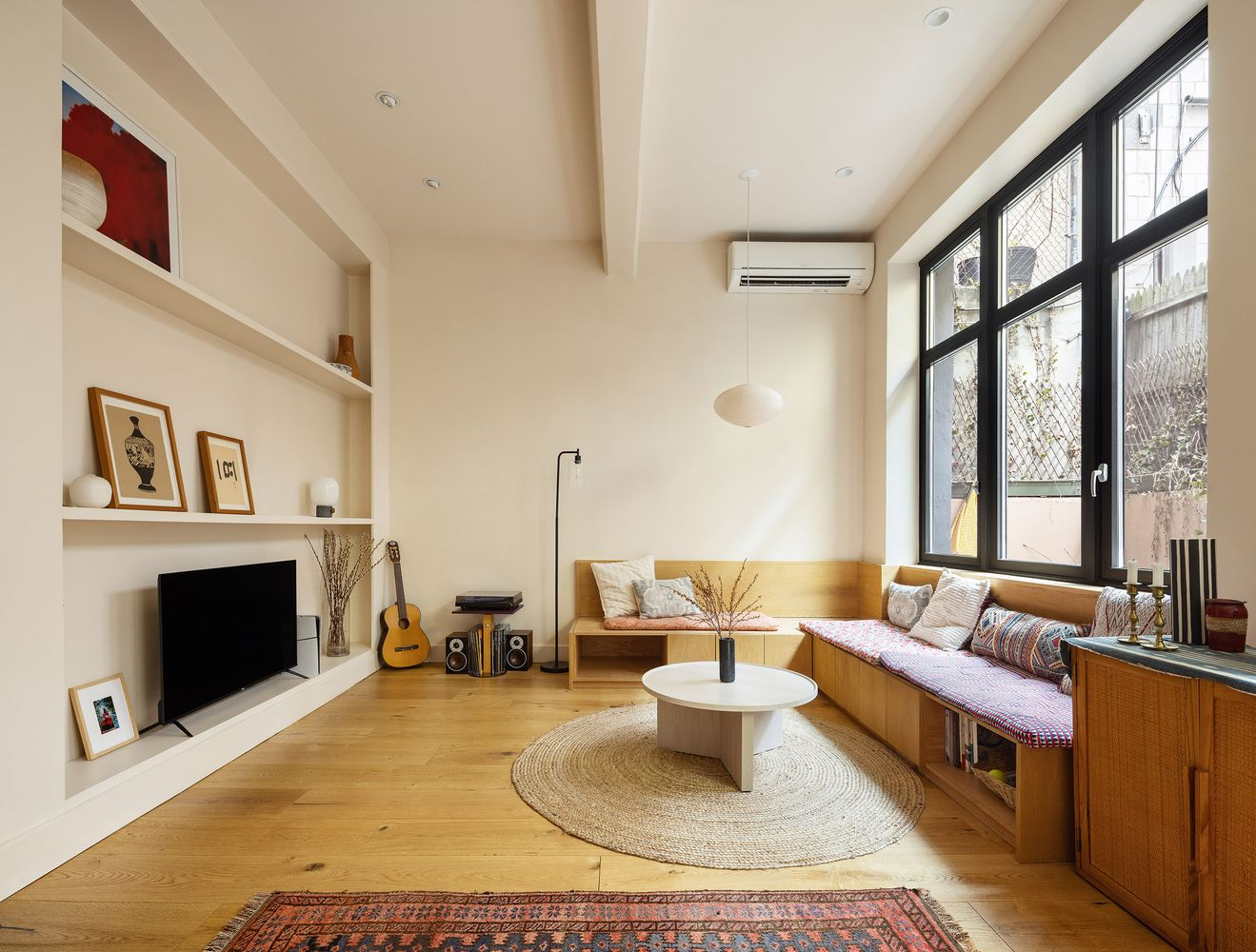 brooklyn condo living room with wall of windows, built-in shelves