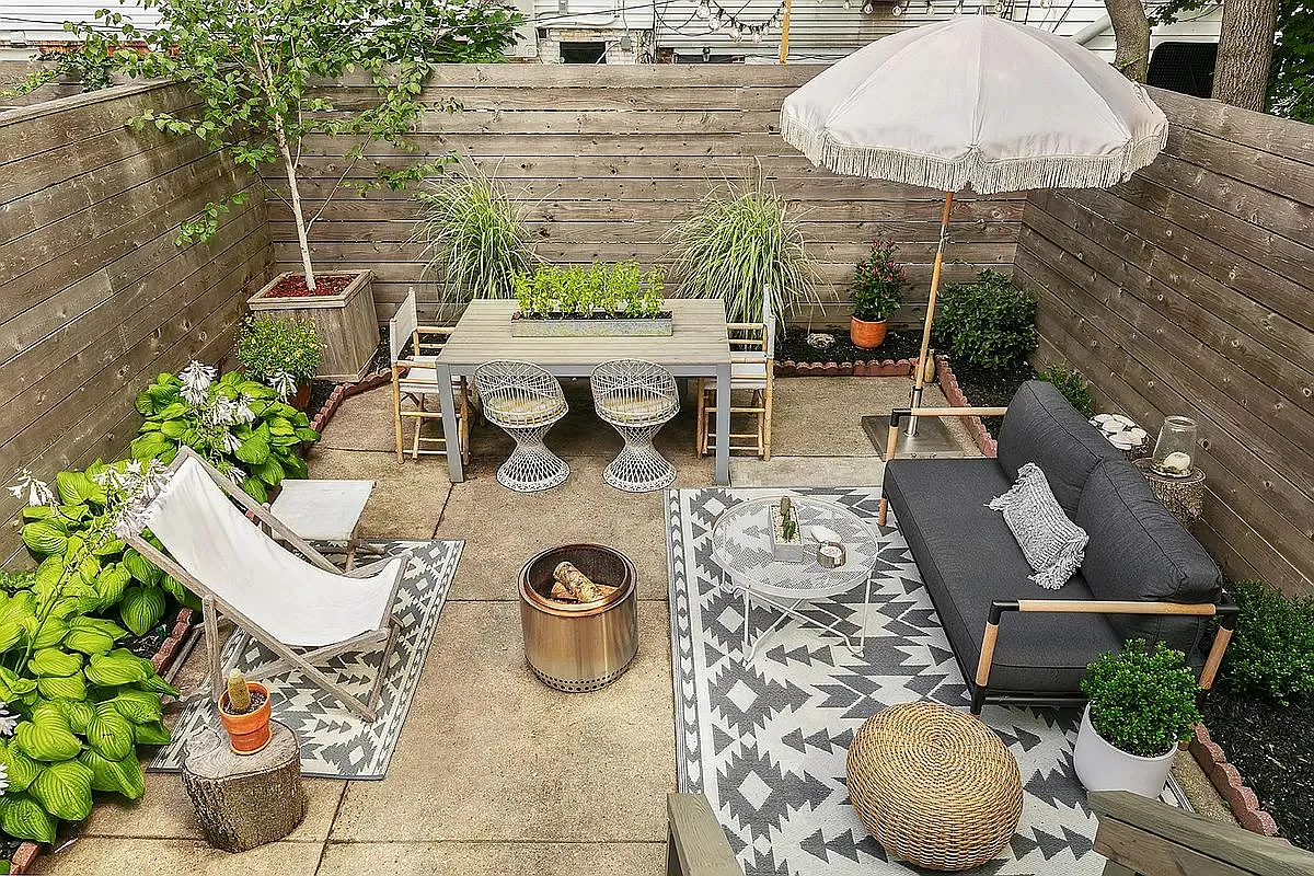 rear yard with paved patio, planting beds, and a horizontal fence