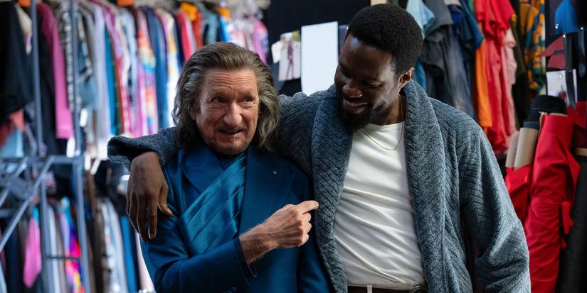 Yahya Abdul-Mateen II with his arm around Ben Kingsley who is pointing to him and they both smile in Wonder Man Episode 7.