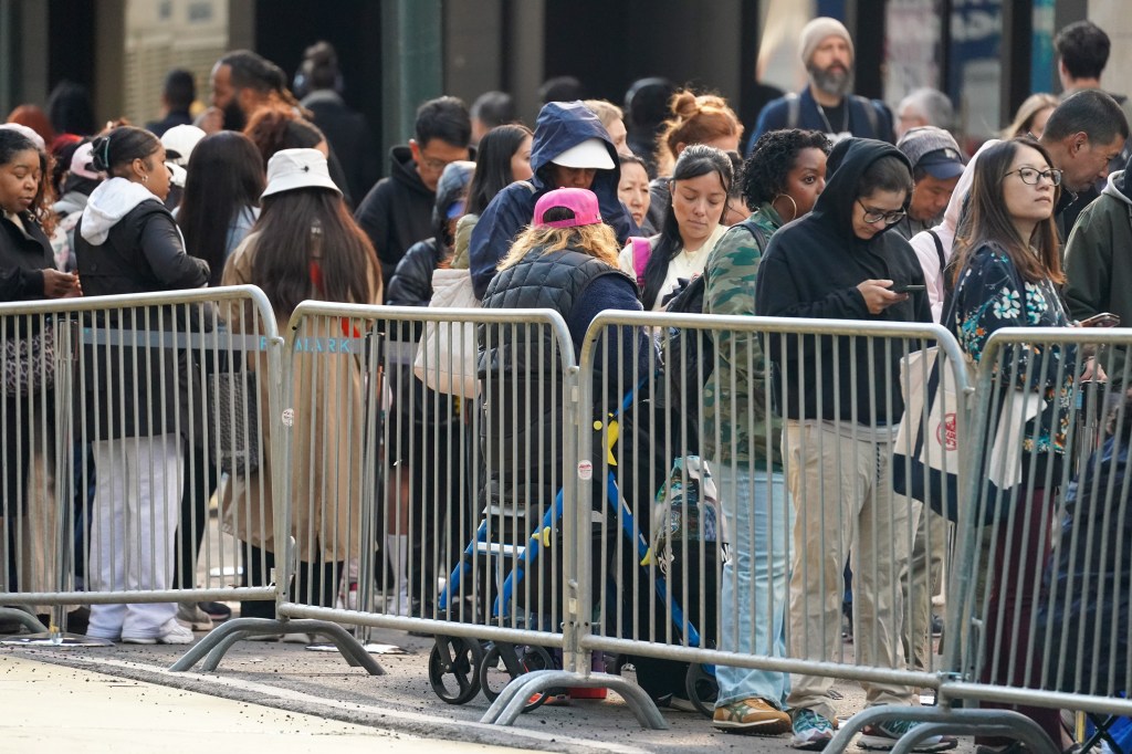 People waiting in line behind metal barricades for the 10 a.m. Primark store opening.