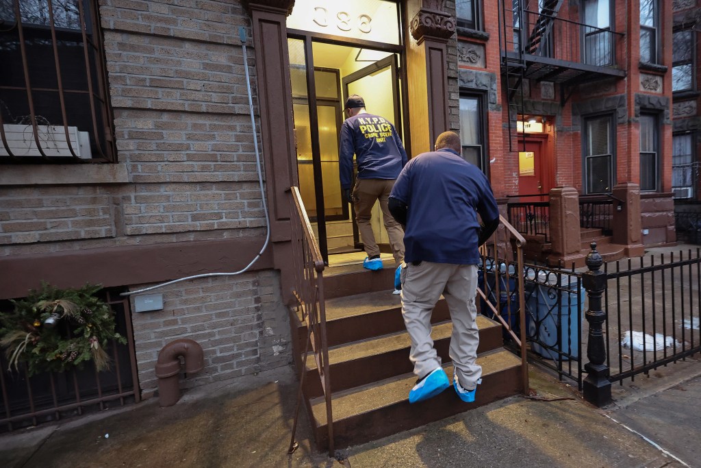 Two men in NYPD Crime Scene Unit attire ascending steps into a building.