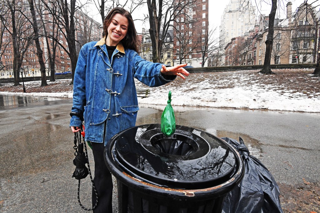 Olivia Bannerman, the "Poop Fairy," disposing of a green bag into a public trash can.