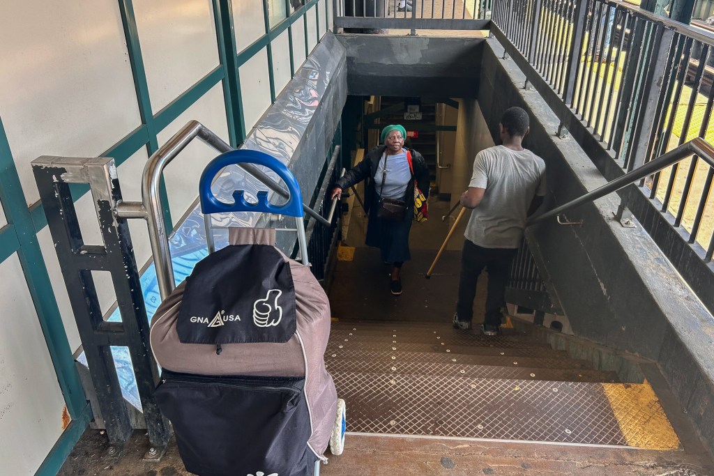 A man with a cane helped carry a bag for Joan Graham up the stairs to the platform at the Kingsbridge Road station in The Bronx,