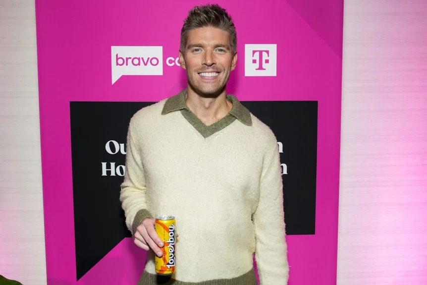 Kyle Cooke holds a can of Loverboy at a step and repeat.