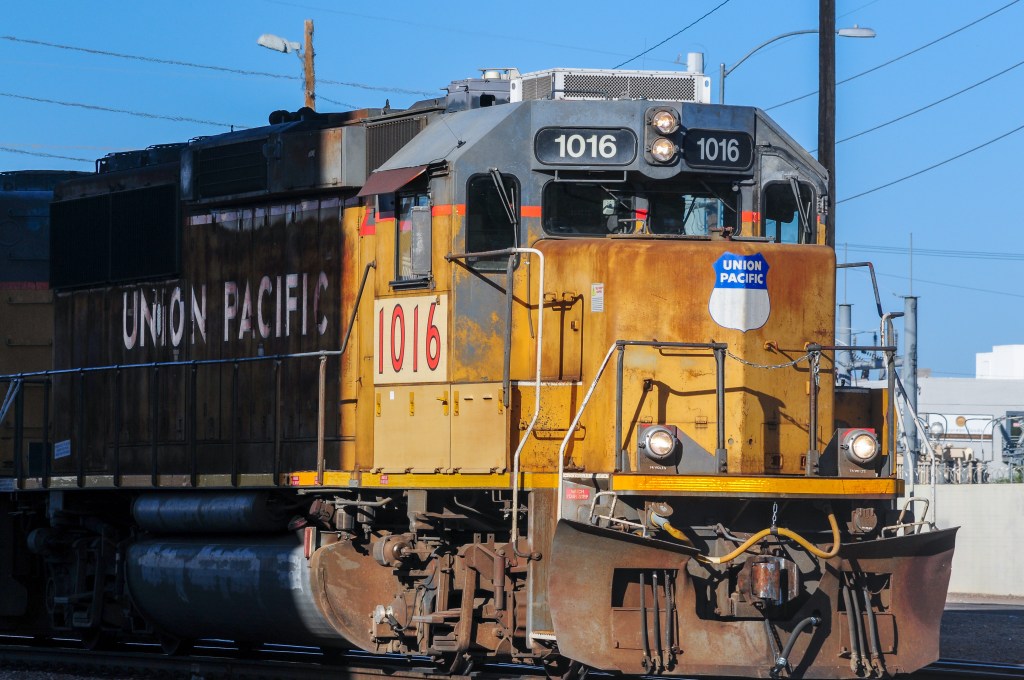 Front view of Union Pacific locomotive 1016 at a rail crossing.