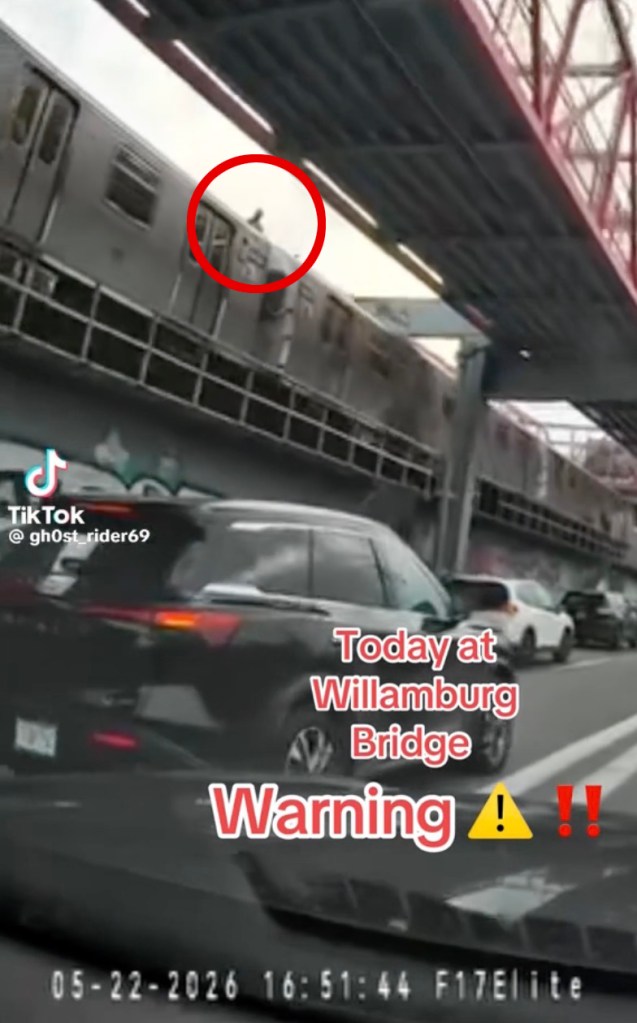 A person riding on top of a subway car crossing the Williamsburg Bridge.