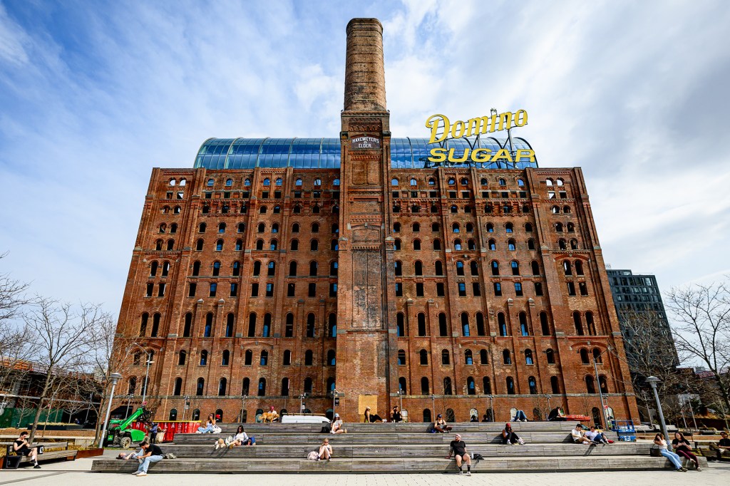 Domino Sugar Refinery building with a tall brick chimney and "Domino Sugar" sign on top.