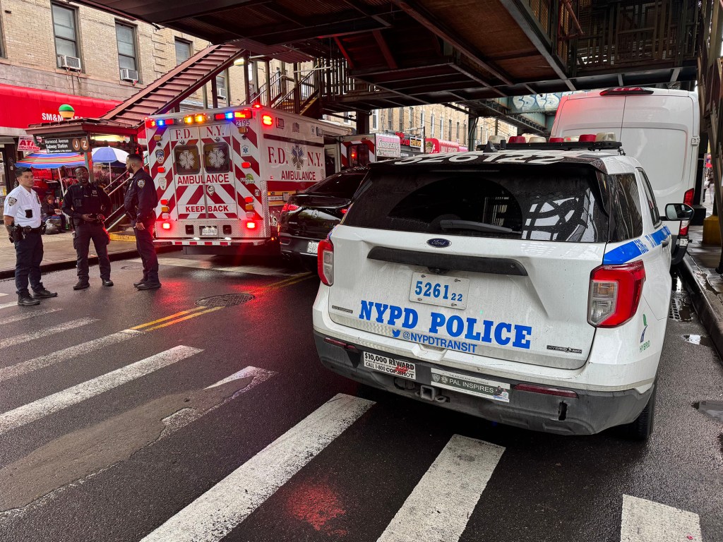 An NYPD police car and an FDNY ambulance with flashing lights at the Norwood Avenue subway station.