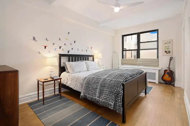 Cozy bedroom featuring a black bed with patterned bedding, a nightstand with a lamp, and bird decals on the wall.