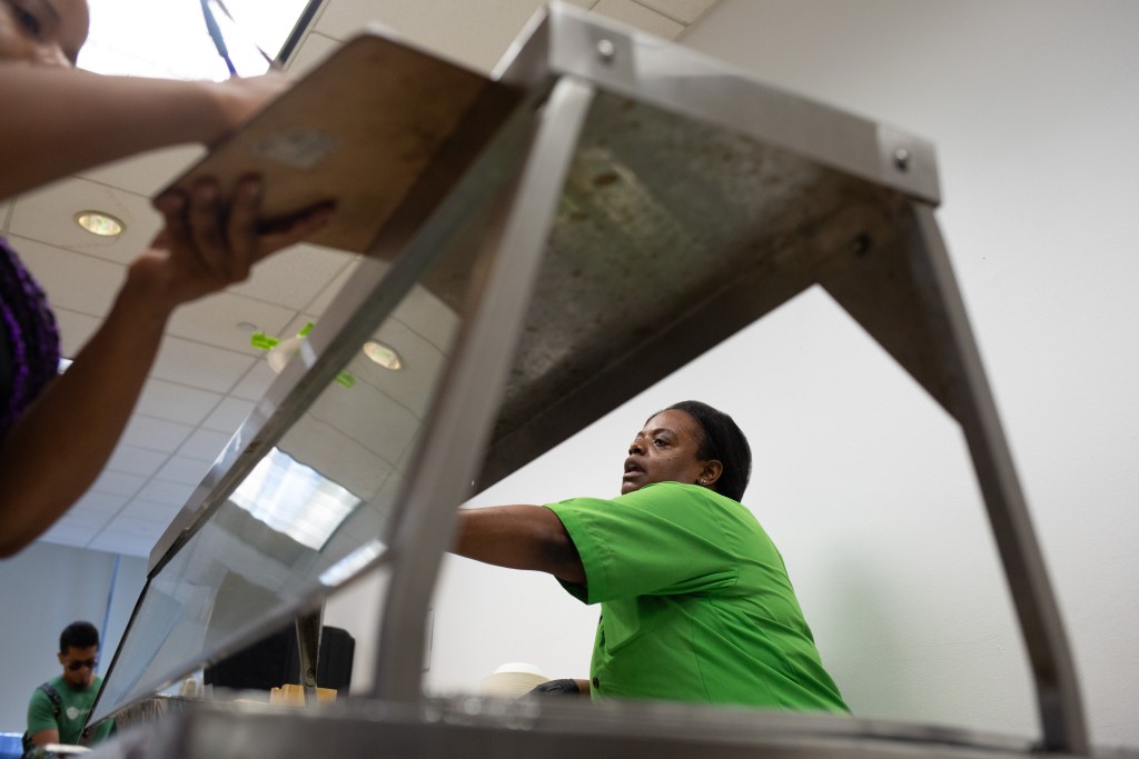 Fortune Society worker Ramona serves lunch to program participants at their Long Island City headquarters.