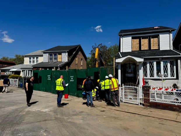 A construction crew boards up a destroyed house on 130th St. in Queens, the day after a massive explosion there. (Rebecca White / New York Daily News)