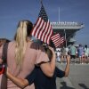 A woman stands with her children as her husband prepares to set sail on the aircraft carrier USS Gerald R. Ford from the Naval Station Norfolk on June 24, 2025, in Norfolk, Va. More than 10 months later the carrier and its crew is still at sea.