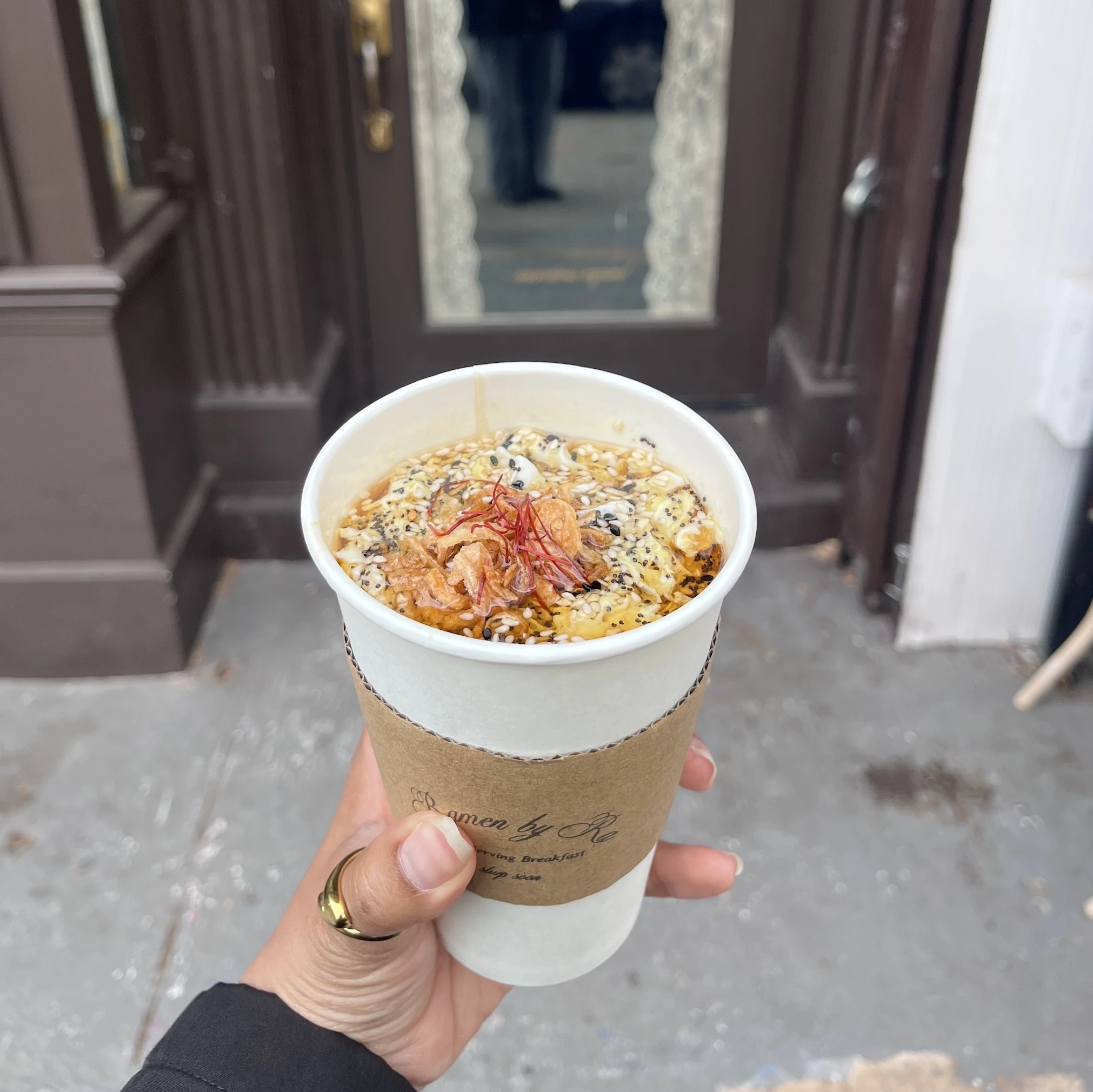 A hand holding a to go cup of ramen