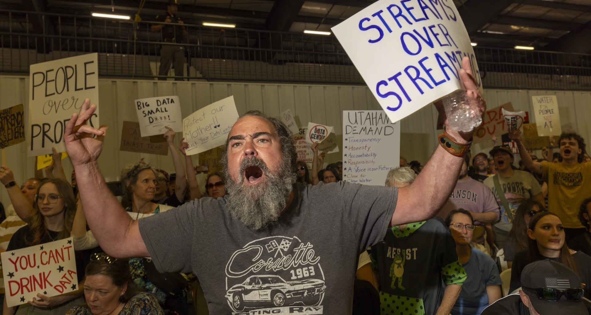A passionate protestor shouts with a sign demanding water rights amid a crowd holding various protest signs.