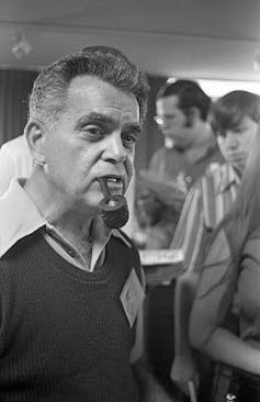 Black-and-white photo of middle-aged white man smoking a pipe.