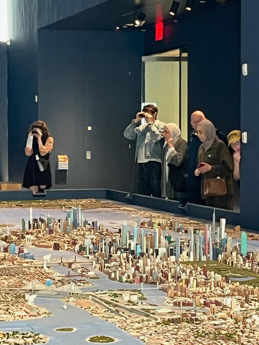 Exhibit goers look over "He Built This City" by Joe Macken. (Karyn Miller-Medzon/Here & Now)