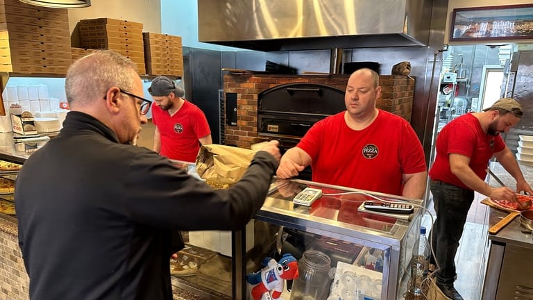 A man pays for pizza at Lo Duca Pizza, May...