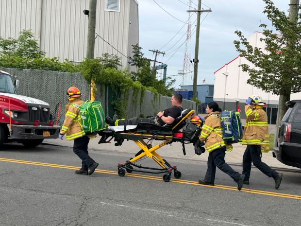 An injured FDNY firefighter is taken to an ambulance after an explosion and fire at a shipyard on Richmond Terrace between Lockman and Andros Aves. on Staten Island on Friday, May 22, 2026. (Rose Abuin / New York Daily News)