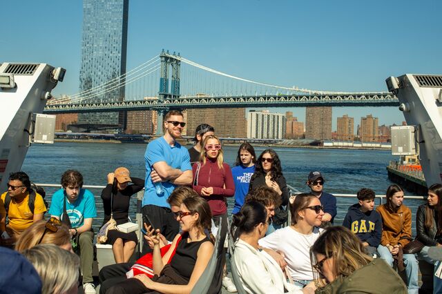a crowd of passengers on the deck of the ferry. Manhattan bridge in the distance.