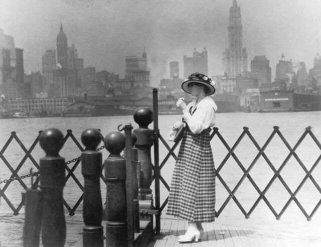 A woman waits for a ferry to Manhattan circa 1905.