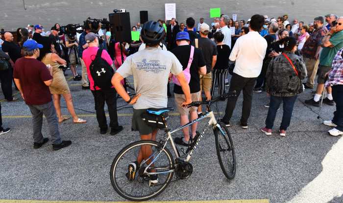 A cyclist watches on as residents protest against the redesign. Photo by Ramy Mahmoud.