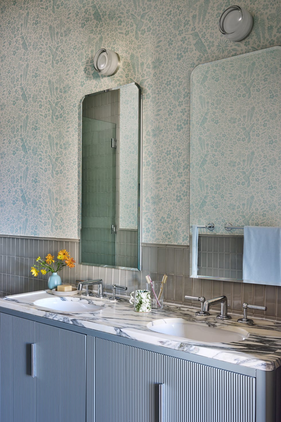 Bathroom vanity with mirrors, floral wallpaper, and sink area.