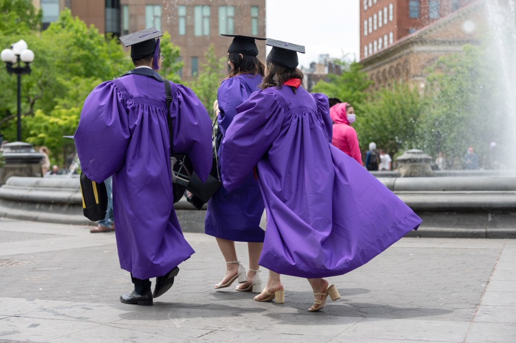 NYU students in purple caps and gowns walking through Washington Square Park.