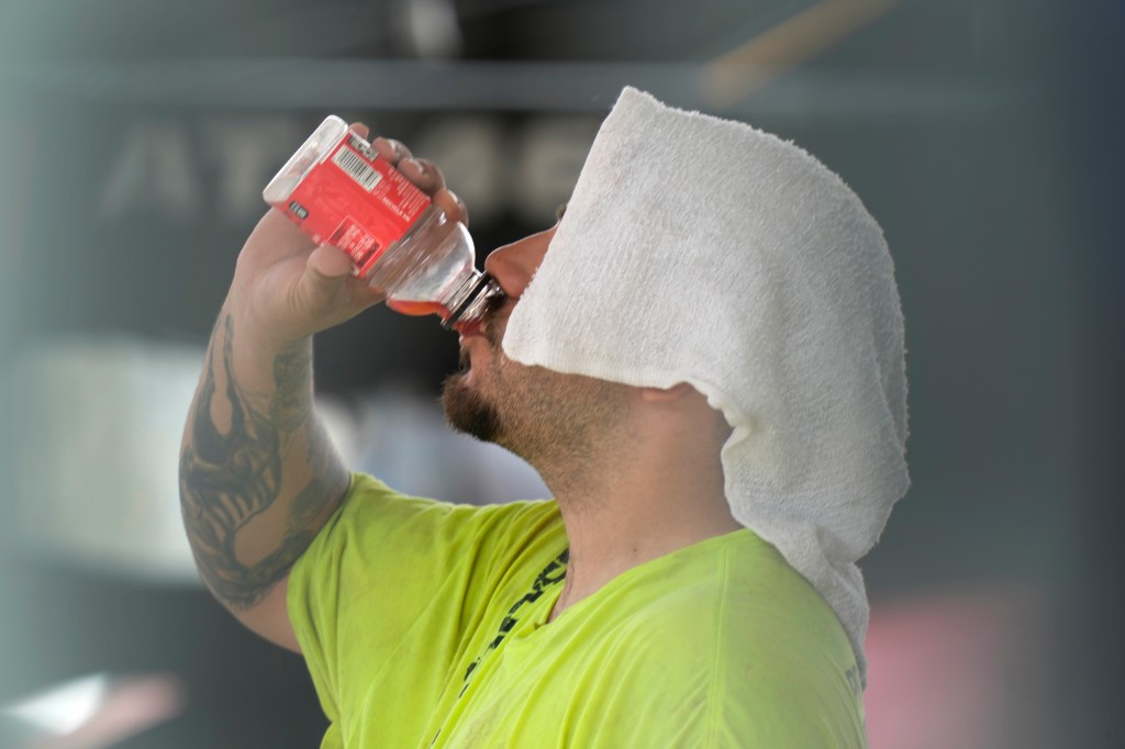 man drinks and has towel over his head