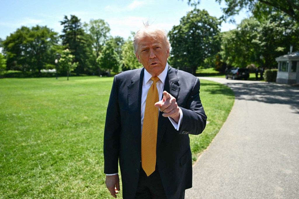 Donald Trump pointing at the viewer while standing outdoors.