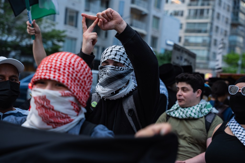 Antizionist protesters gathered outside the Park East Synagogue, many wearing keffiyeh scarves and some making hand gestures.