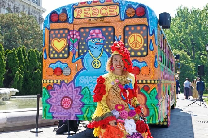 Artist Carmen Paulino stands beside one of the psychedelic buses featured in the &ldquo;Flower Power&rdquo; exhibit, this one created by artist Snoeman.