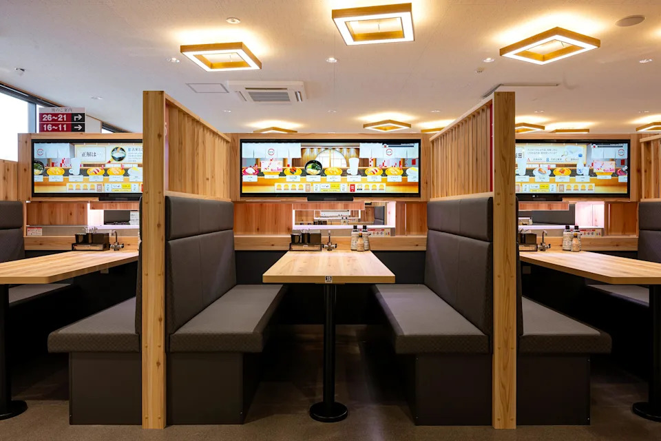 A restaurant dining room with booths with digital kiosks at them.