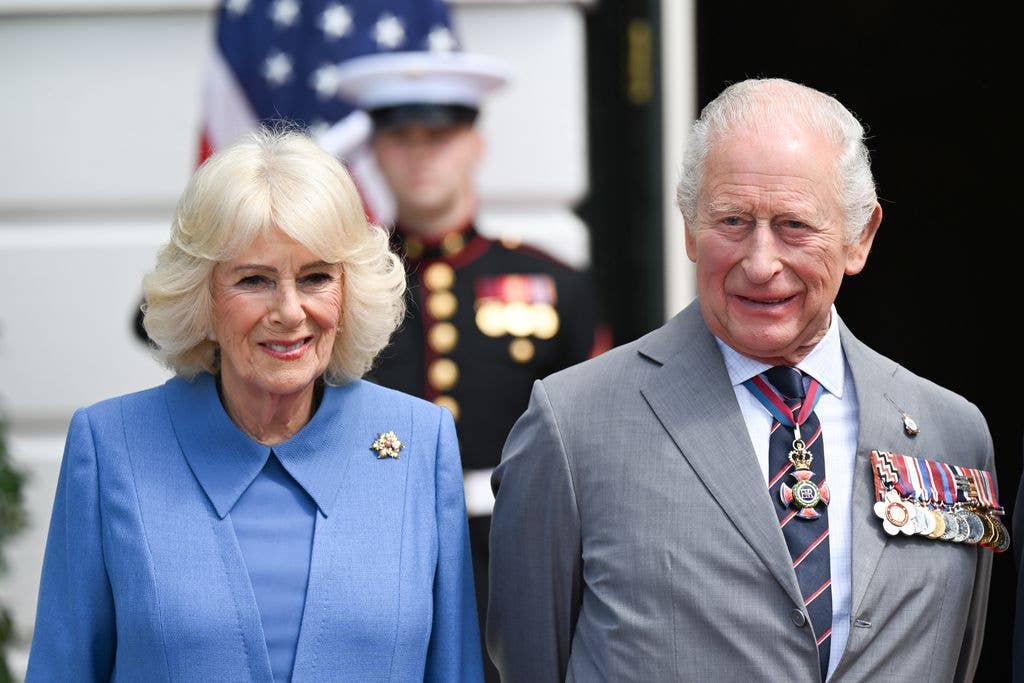 Queen Camilla in blue dress beside charles in suit