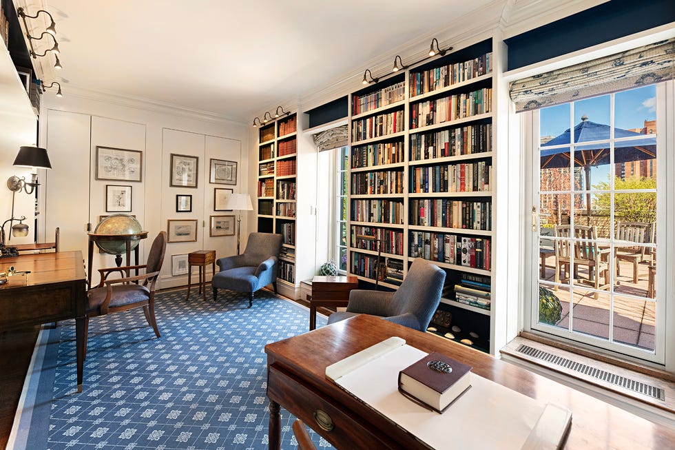 Home office with a large bookshelf and a view of an outdoor patio. Home office with a large bookshelf and a view of an outdoor patio.