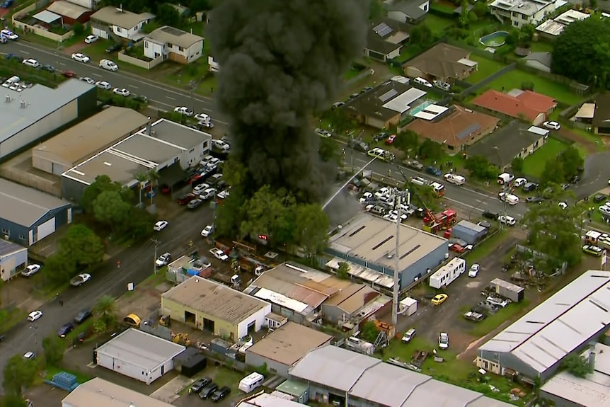 Black smoke rising from a building in an industrial district.