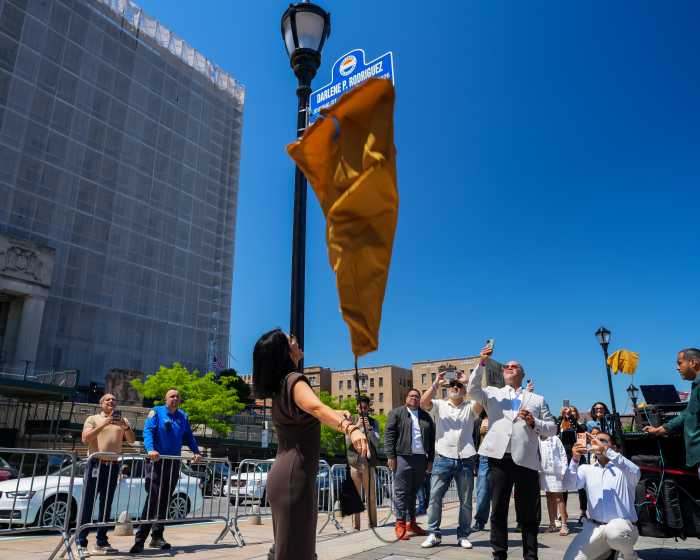 Journalist Darlene Rodriguez removes the cloak on her street sigh in Lou Gehrig Plaza.