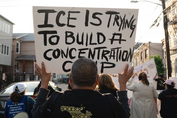 A man holds a sign that reads ''ICE is trying to build a concentration camp'' during an International Workers' Day rally and mar