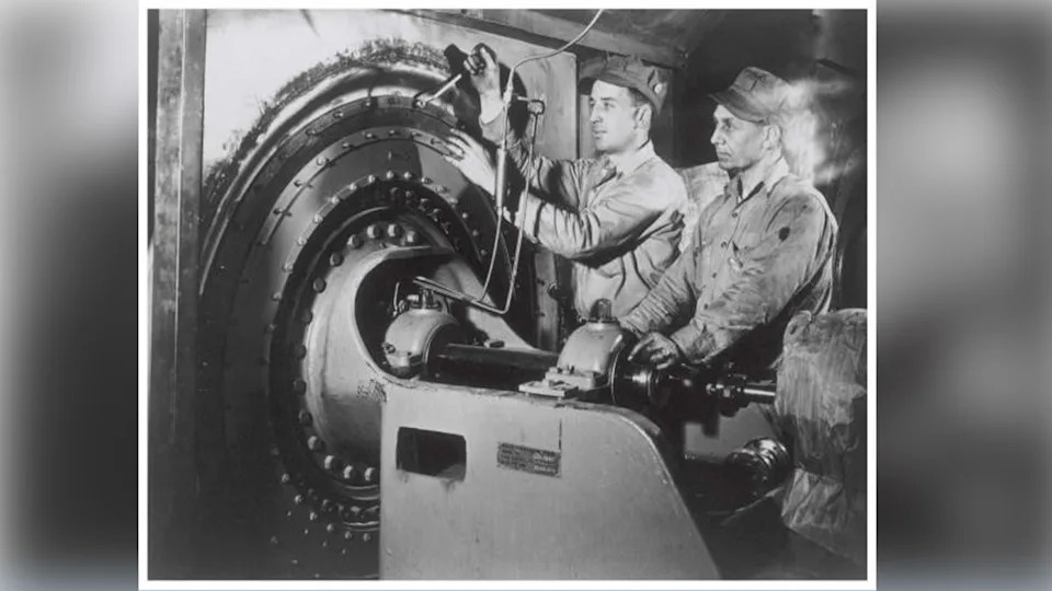 Men operating a cylindrical machine