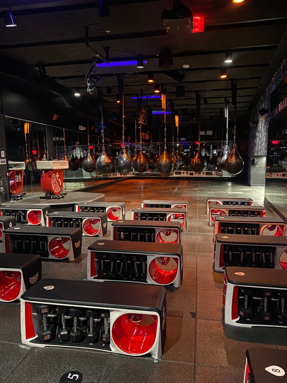 Gym interior with workout stations and hanging boxing bags.