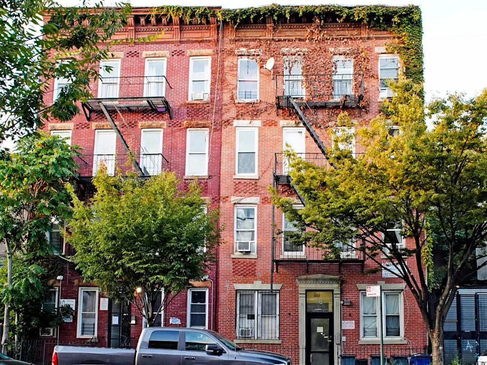 A red brick building in Brooklyn with trees in front of it