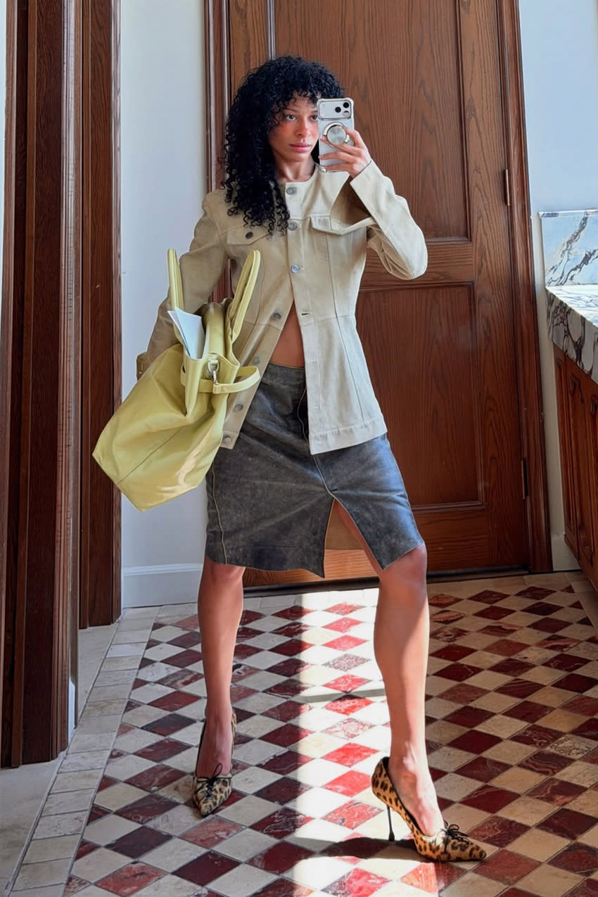 a woman wearing a taupe button-down collarless jacket, a leather distressed skirt, and cheetah print heels