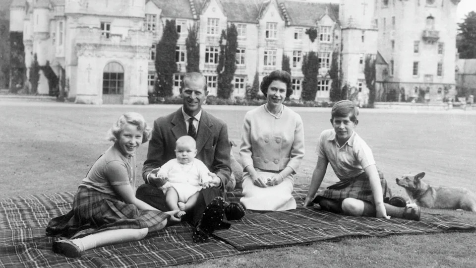 Queen Elizabeth II and Prince Philip with their children Andrew (centre), Anne (left) and Charles sitting on a picnic rug outside Balmoral Castle in Scotland, 8th September 1960