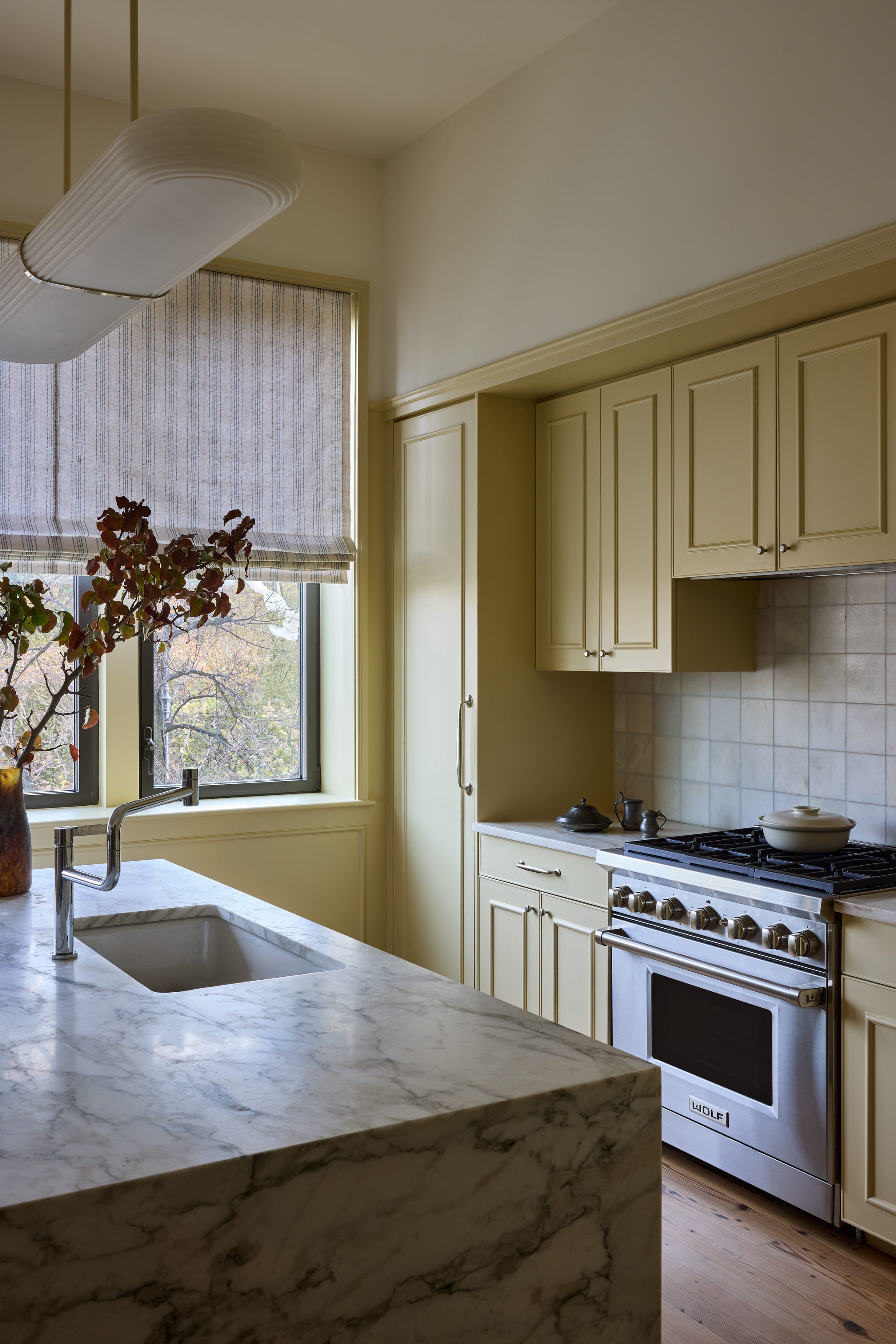 Modern kitchen with marble counter and yellow cabinetry.