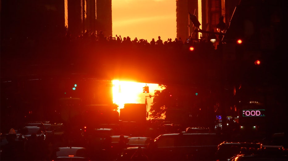 NEW YORK, NY - JULY 11: People photograph the sun setting along 42nd Street from Park Avenue during the summer Manhattanhenge on July 11, 2022, in New York City. (Photo by Gary Hershorn/Getty Images)
