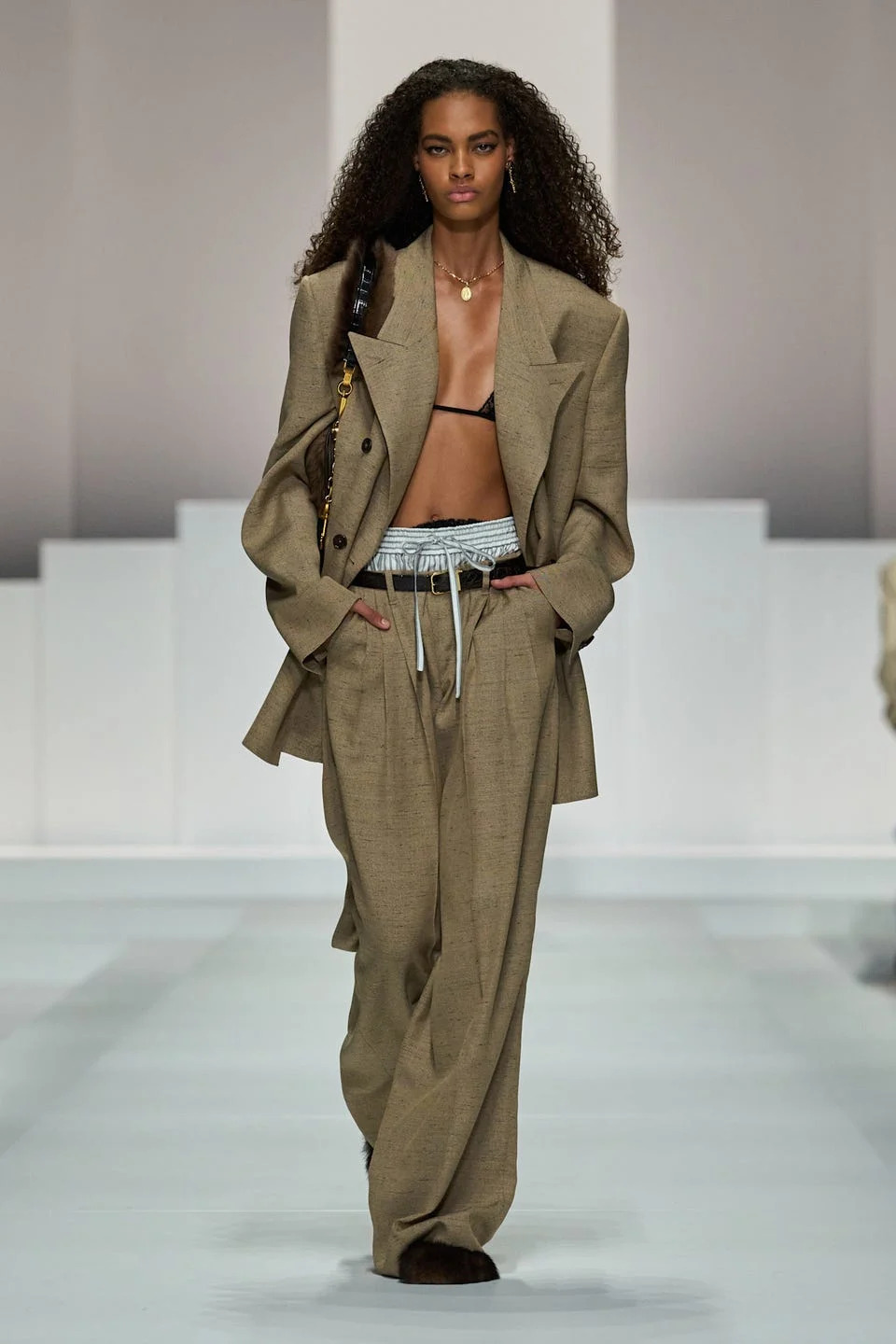 Model walking on a runway wearing a stylish outfit.