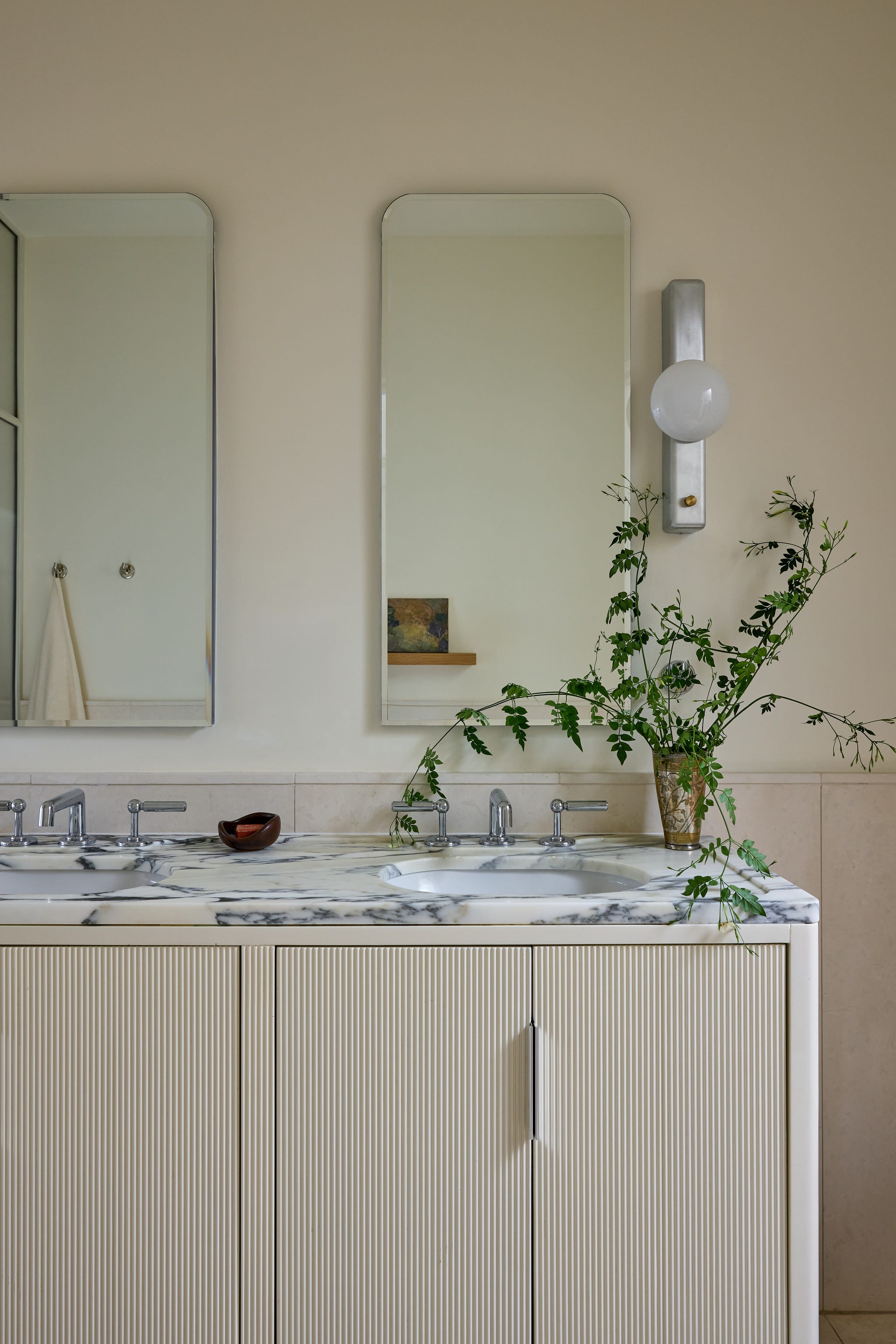 Modern bathroom vanity with mirrors and plants.