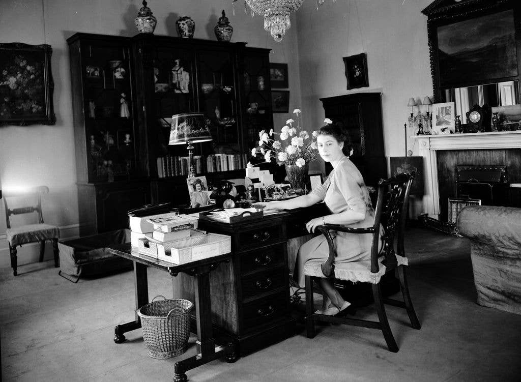 Princess Elizabeth sitting at her desk in her apartment at Buckingham Palace
