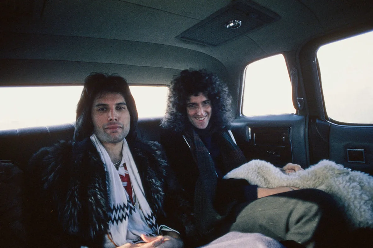 Freddie Mercury and  Brian May riding in the back of a car, in Los Angeles, California, February 1977