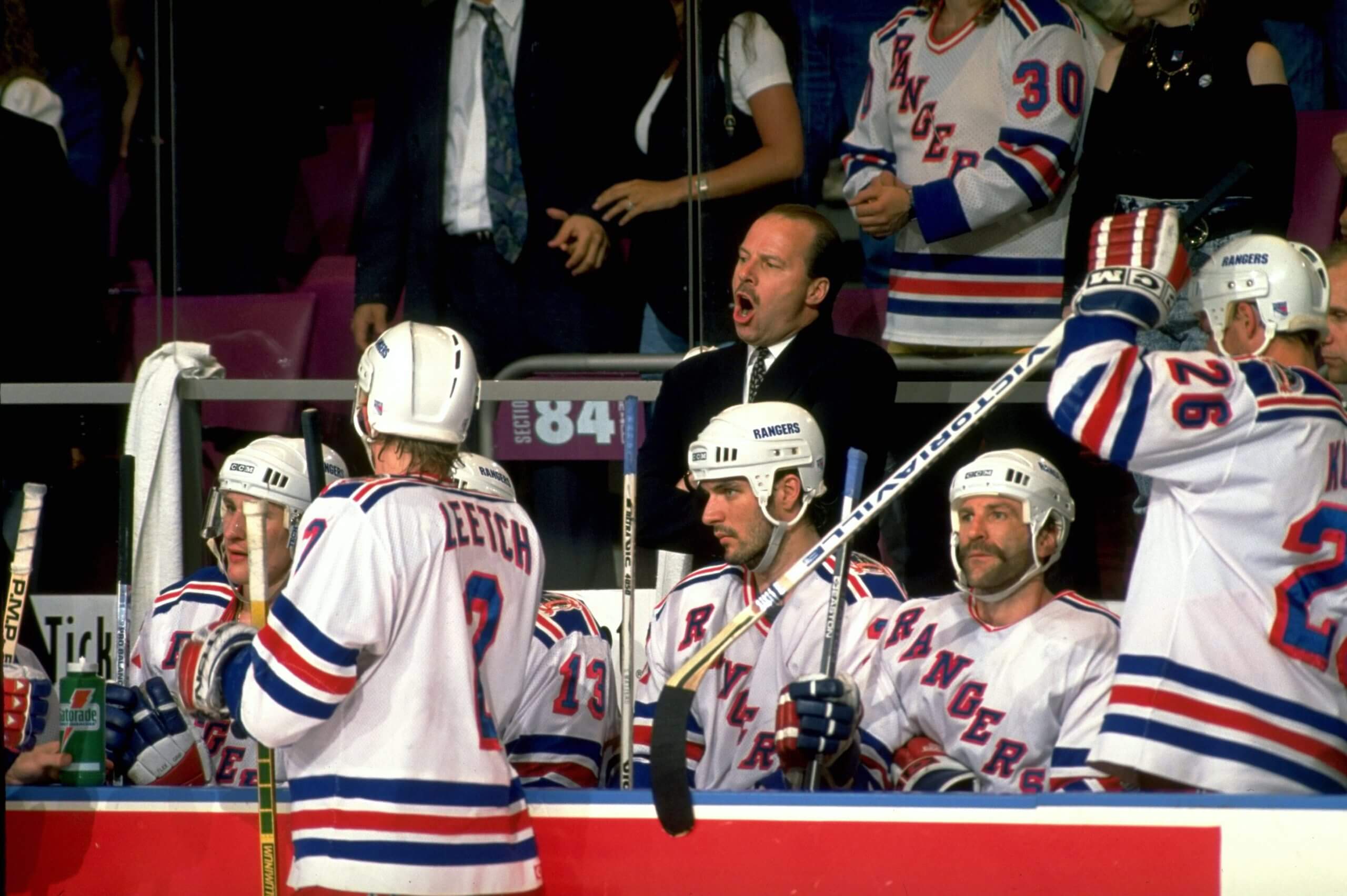 Mike Keenan yells from behind the Rangers' bench during a game in the 1994 Stanley Cup Final while his players look on.