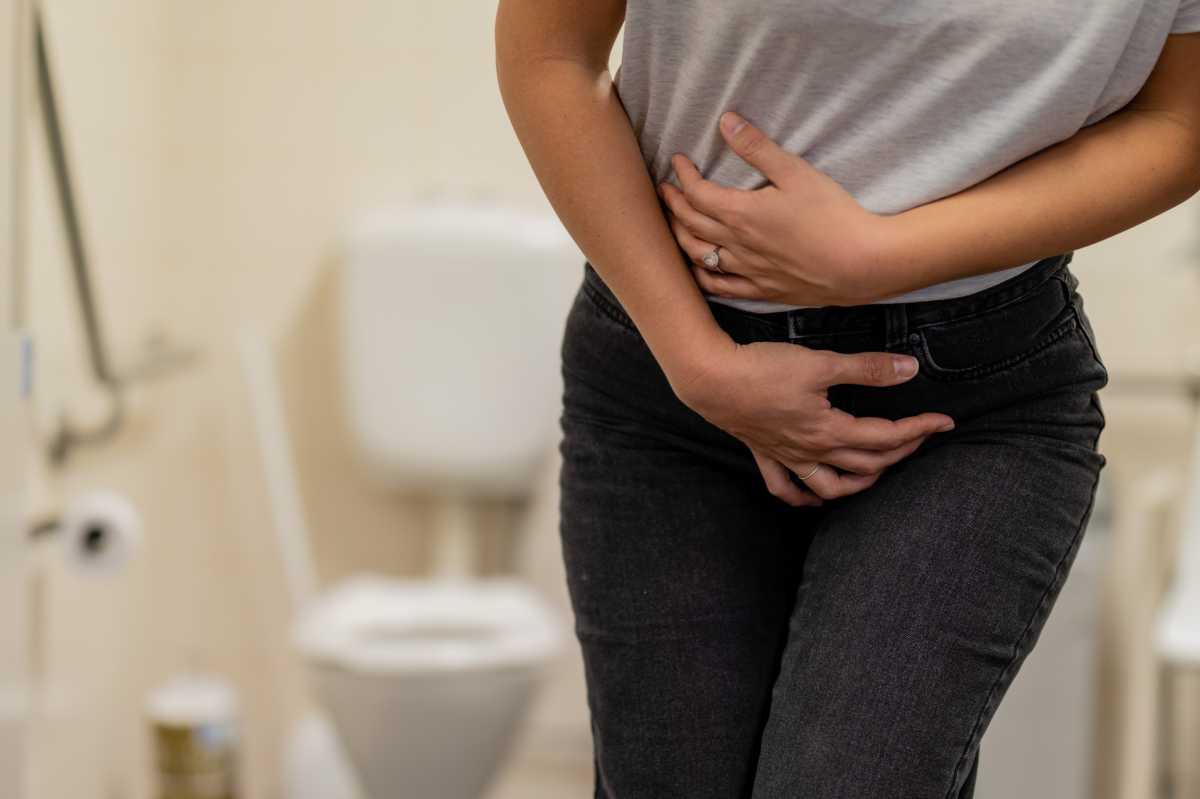 person with IBD holding their abdomen in the bathroom